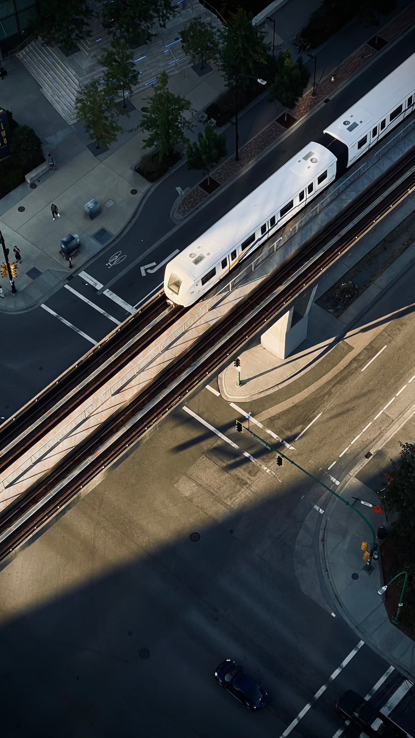 A view from above on a large street intersection with a SkyTrain car rolling on a track