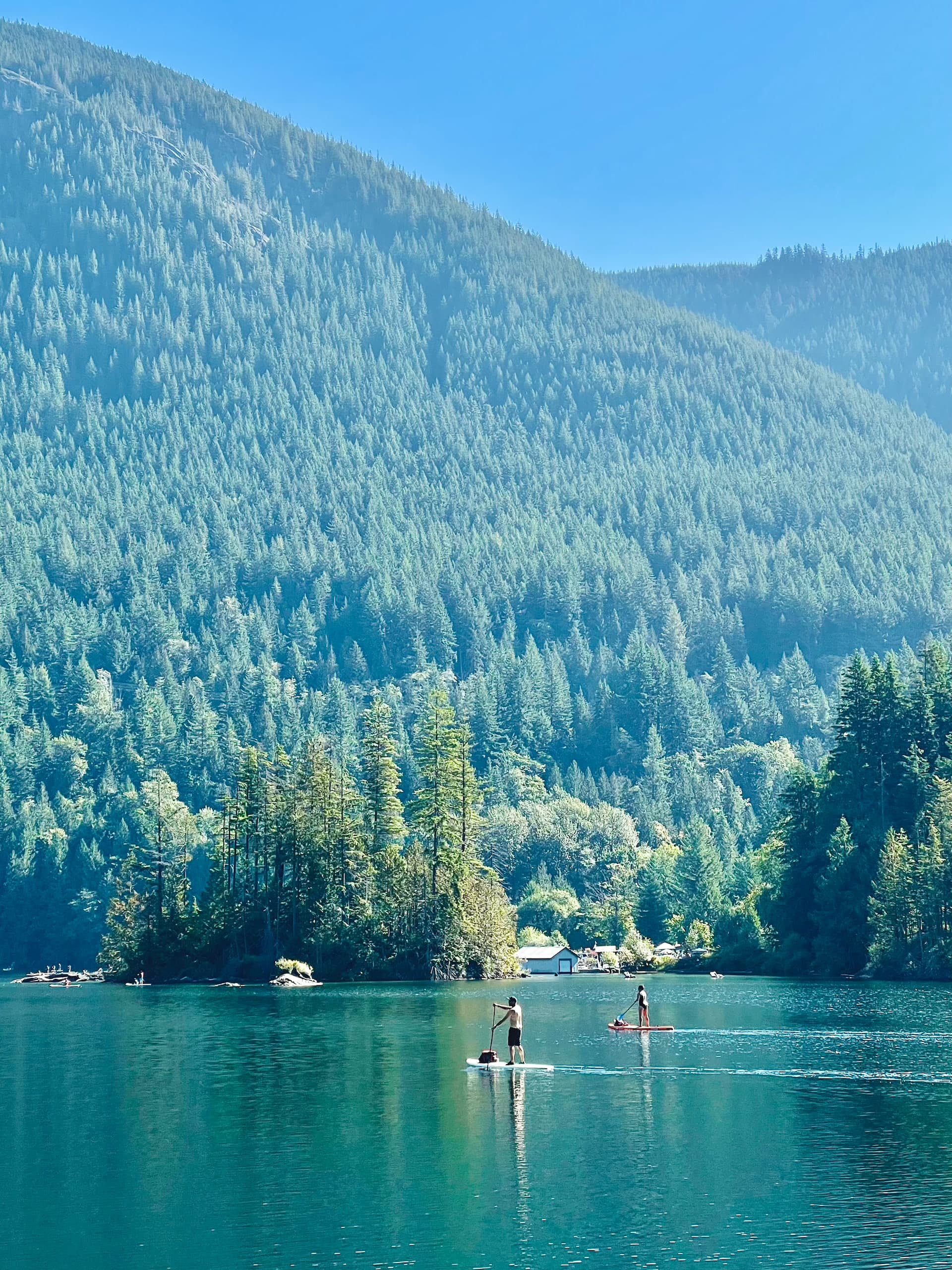 2 people paddleboarding on a lake with a mountain the background