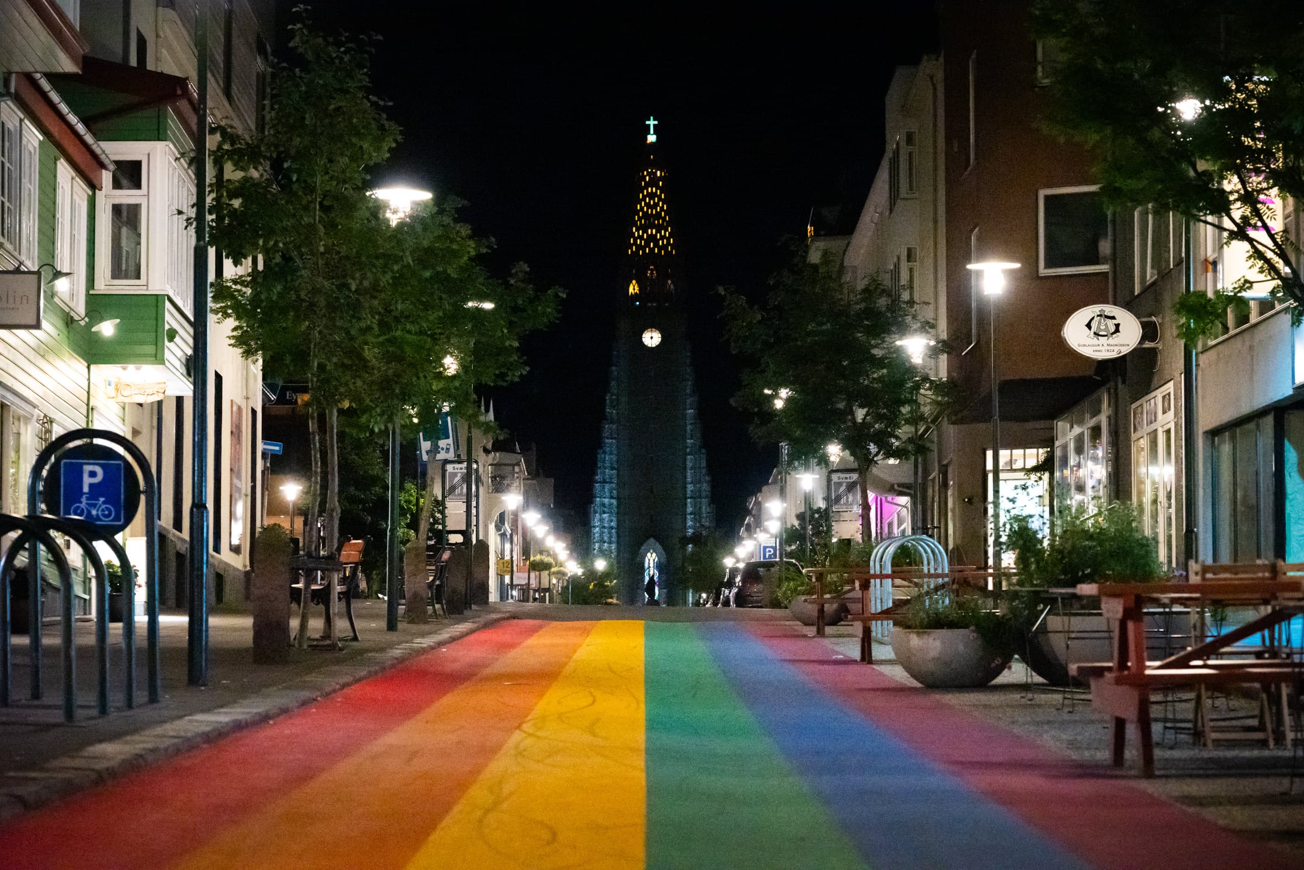 Street with a rainbow road, shops on the sides, and a church in the distant