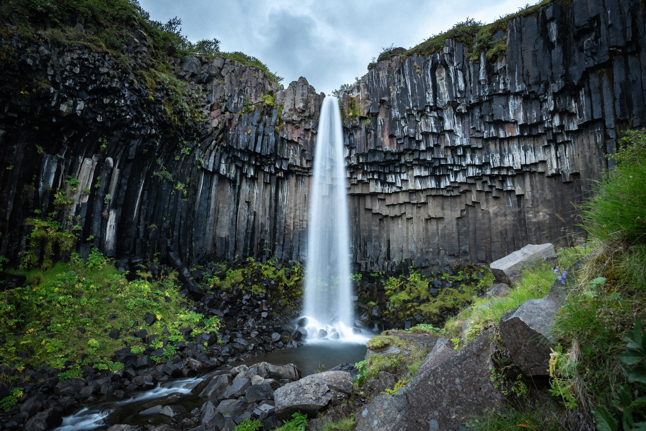 A waterfall at the center surrounded by upside-down basalt columns